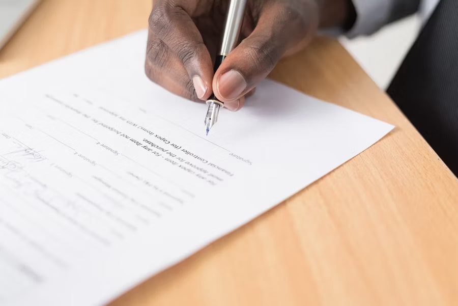 Professional signing a document to navigate complex standards of XBRL with a fountain pen on a wooden desk.