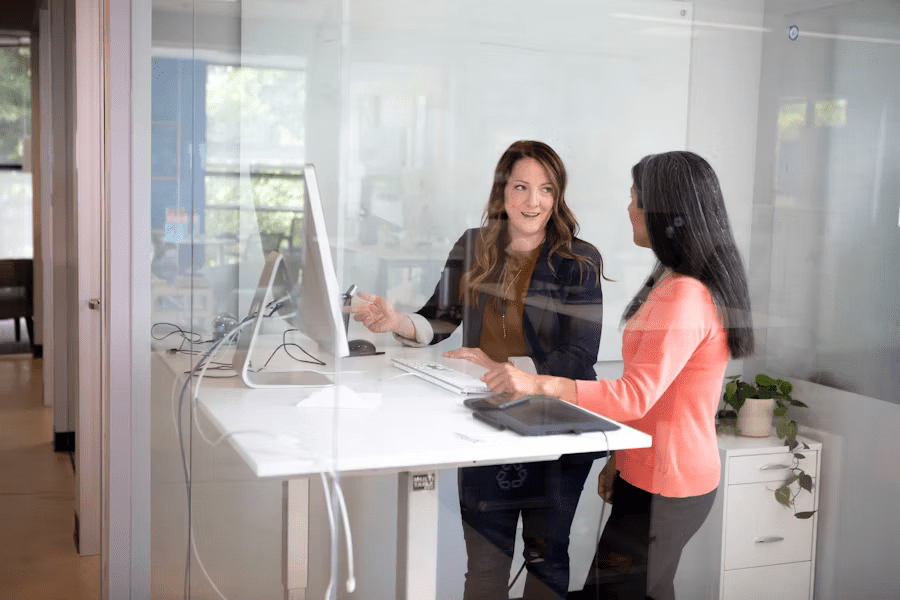 Coworkers demonstrate attention to detail while collaborating on a project at a modern office standing desk.