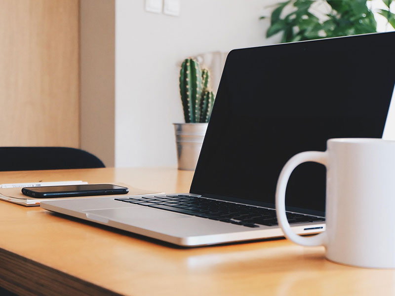 Laptop on wooden desk with coffee mug featuring Easy Edit Technology for a streamlined modern workspace