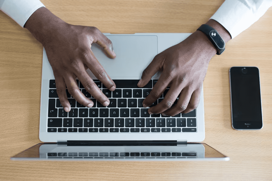 Hands typing on a laptop with Accuracy, Speed, Personalized Service on a wooden desk next to a smartphone.