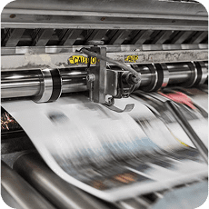 Industrial laminating machine processing printed sheets through metal rollers with high-speed motion blur effect.