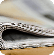 Folded newspapers on a wooden table for professional press release distribution and media outreach.