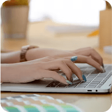 Hands typing on a laptop keyboard to deliver professional typesetting services in a modern office setting.