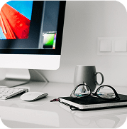 Modern desk setup with DGAR filing software on a monitor, keyboard, mouse, and glasses on a white office desk.