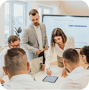 Professionals discussing data on a tablet during a collaborative Shareholder Meeting in a modern, bright office.