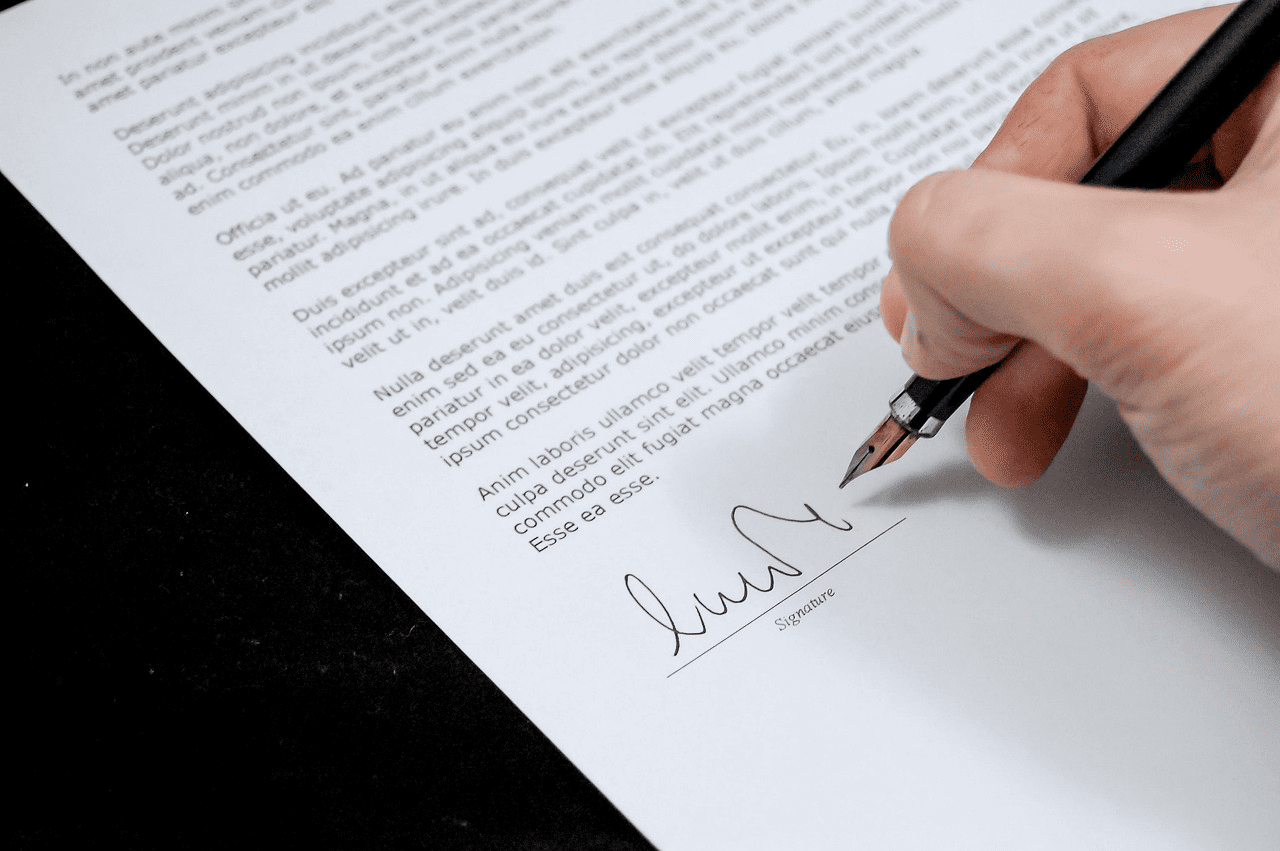 Hand signing a professional contract with a fountain pen, showcasing extensive expertise in legal documentation