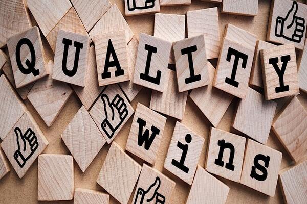 QUALITY wins wooden tiles with thumbs up icons, showcasing the value of high-quality typesetting services.