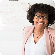Smiling woman in a pink blazer at a whiteboard to perform broker search and distribution.