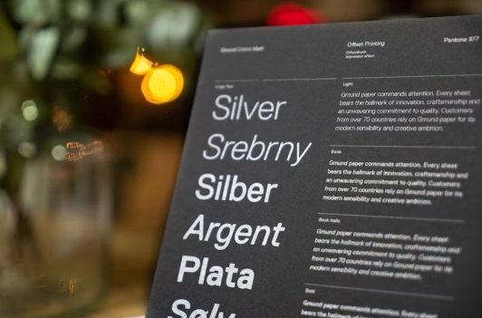 Silver ink on black paper displaying multilingual fonts for professional Rush Typesetting and premium offset printing.