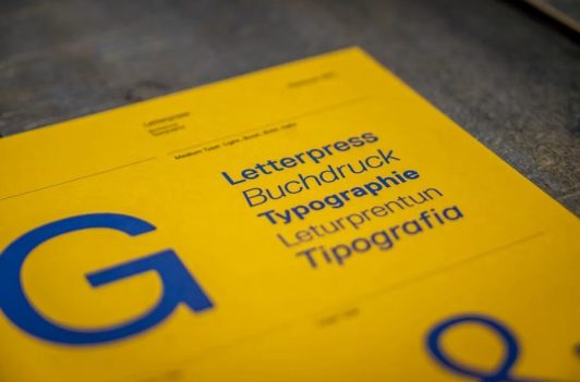 Yellow typography card featuring blue text and terms for Single-Source Typesetting, letterpress, and buchdruck.
