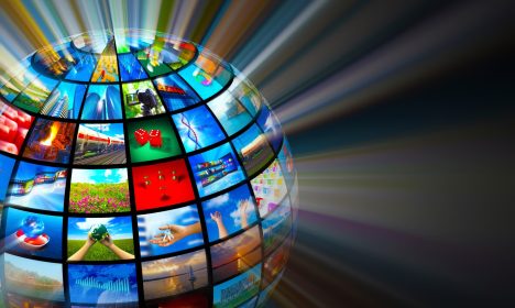 Glowing digital globe of media screens and light rays, illustrating global newswire distribution and digital news reach.